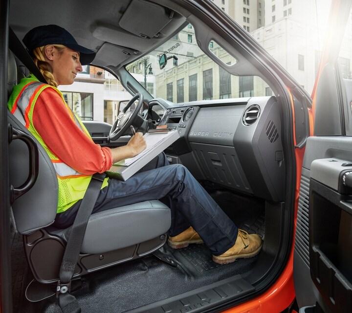 Worker writing on clipboard in passenger seat of 2024 Ford F-750 Crew Cab in Tangier Orange