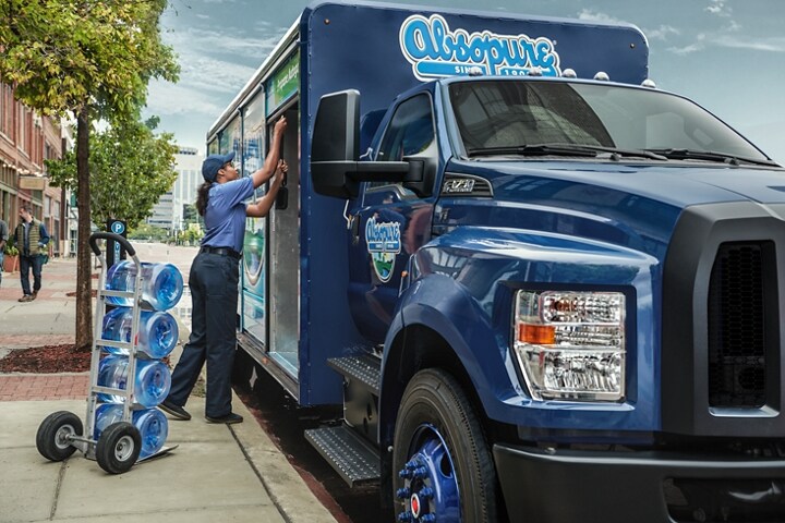 Primer plano de un trabajador que descarga agua de una camioneta Ford F-750 Regular Cab 2024 con mejora para bebidas en Blue Jeans