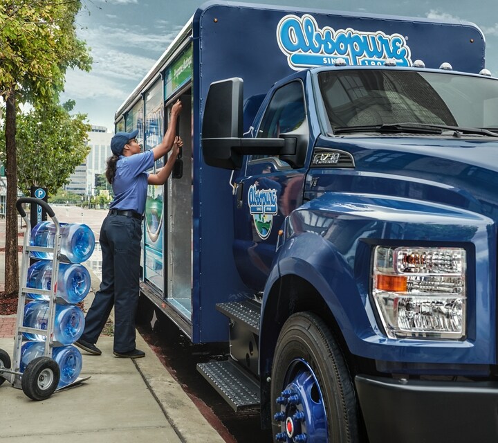 Close-up on worker unloading water from 2024 Ford F-750 Regular Cab with beverage truck upfit on city street