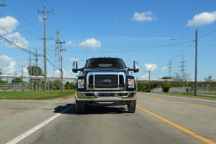 Una Ford F-750 Crew Cab 2024 en Agate Black circulando por una carretera próxima a líneas de teléfono
