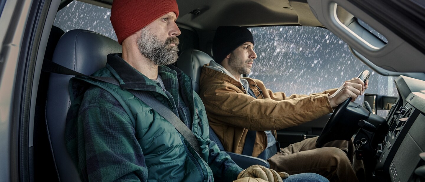 Driver and passenger in winter clothing in front interior of 2026 Ford F-750 Regular Cab