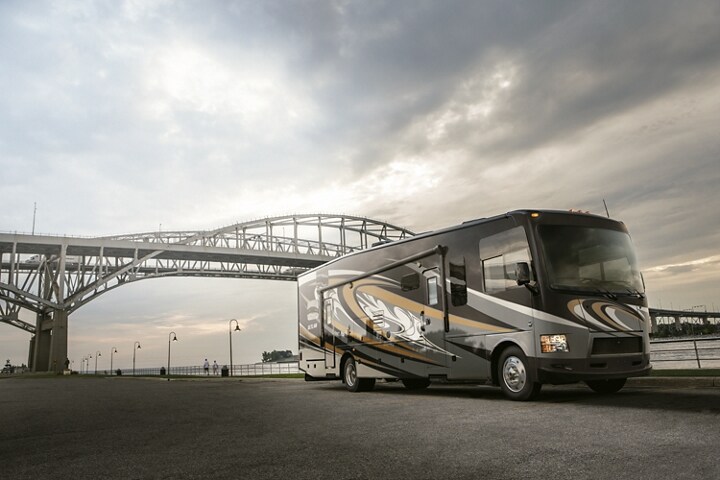 A Class A motorhome on a 2023 Ford F-53 Stripped Chassis being driven under a bridge