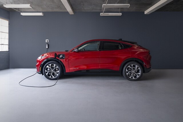 Side view of the 2023 Ford Mustang Mach-E® plugged into a home charger in a garage