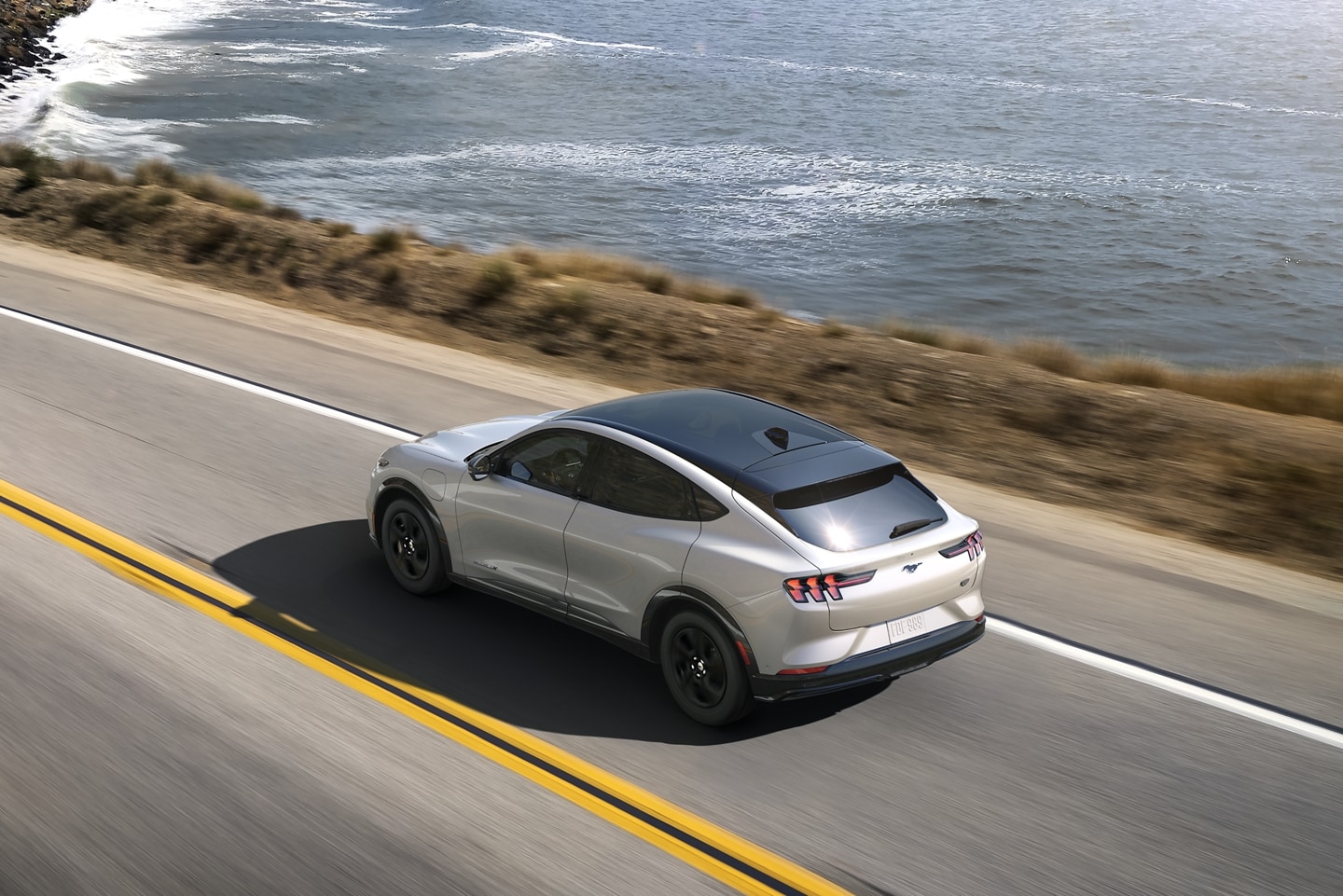 2023 Ford Mustang Mach-E driving with a body of water in the background