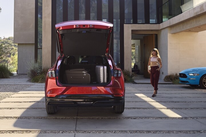 Parte trasera de la Ford Mustang Mach-E® 2023 estacionada en un camino de entrada con un Ford Mustang tradicional estacionado a la derecha