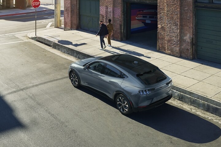 2023 Ford Mustang Mach-E® parked on the street with a couple walking and looking back at it