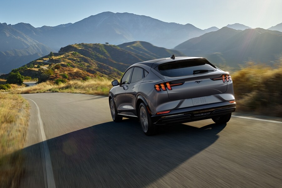 Una Ford Mustang Mach-E® 2023 andando por una carretera en un entorno montañoso