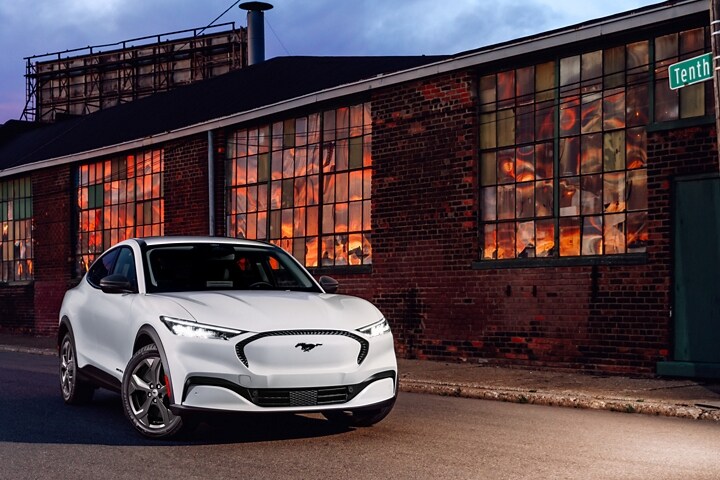 Una SUV Ford Mustang Mach-E® 2023 estacionada fuera de un almacén al atardecer