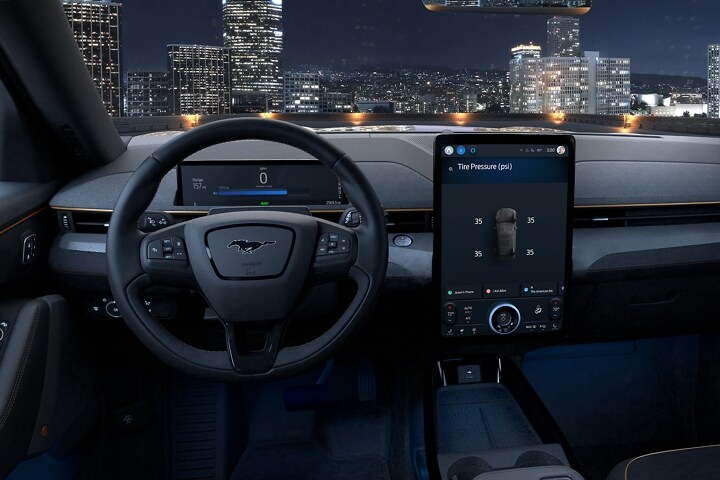Interior view of 2023 Ford Mustang Mach-E® at night with city skyline visible through the windshield