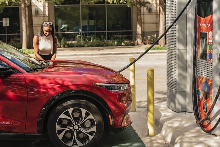 Mujer poniendo un café en una SUV Ford Mustang Mach-E® 2023 en una estación de carga