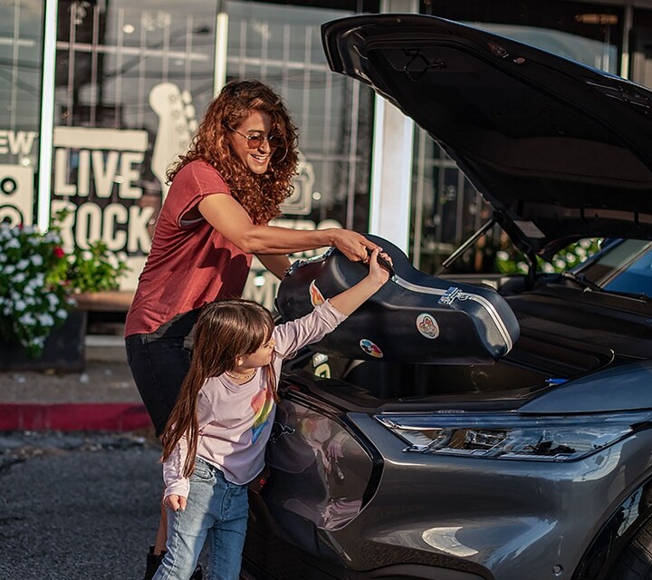 Woman helps child put a musical instrument into the frunk of a 2023 Ford Mustang Mach-E SUV