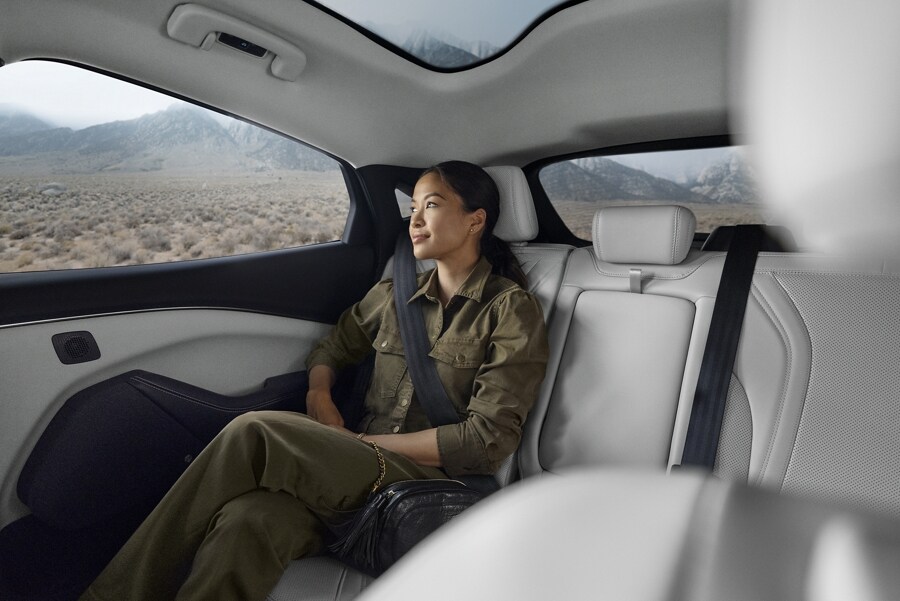 Mujer sentada en el amplio asiento trasero de una Ford Mustang Mach-E® 2023 con mucho espacio para las piernas