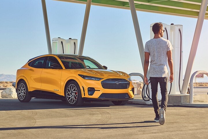 Man walking up to a 2023 Ford Mustang Mach-E® at a charging station