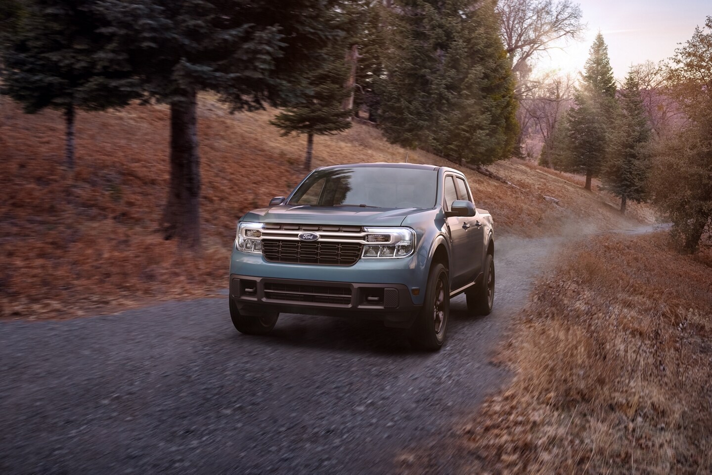2023 Ford Maverick® LARIAT model with available FX4 Off-Road Package drives down a dirt road at dusk