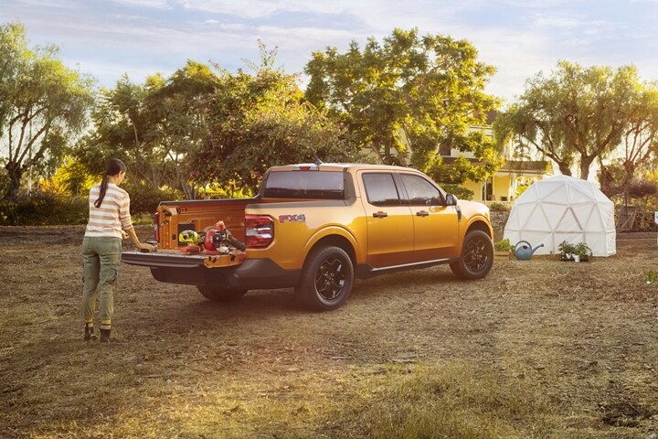 Woman in garden unloads plants from the Cyber Orange 2023 Ford Maverick® XLT multi-position tailgate