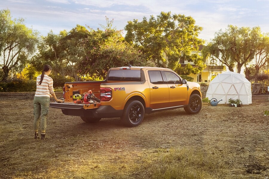 Woman in garden unloads plants from the Cyber Orange 2023 Ford Maverick® XLT multi-position tailgate