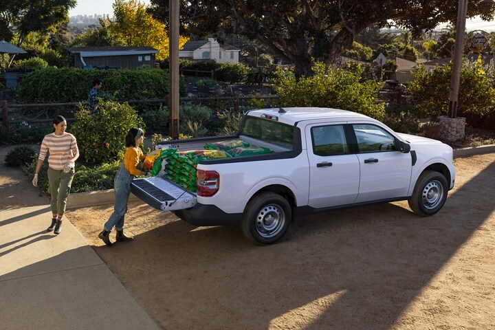 Two women unload supplies from the bed of a 2023 Ford Maverick® XL truck in Oxford White
