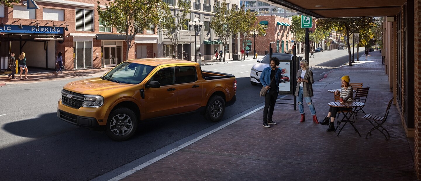 2023 Ford Maverick® XLT model in Cyber Orange with rear view camera parallel parking outside a café