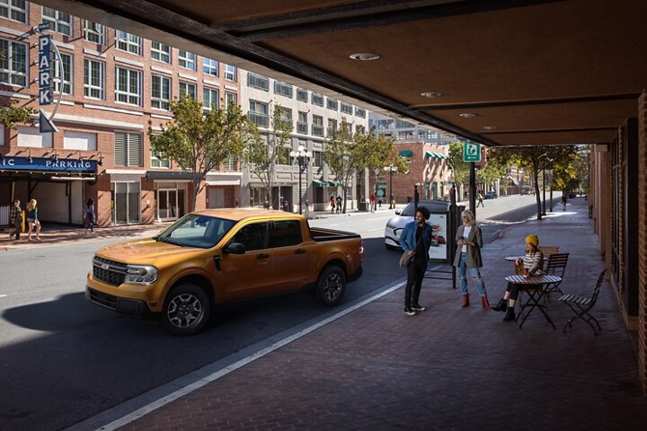 2023 Ford Maverick® XLT model in Cyber Orange with rear view camera parallel parking outside a café