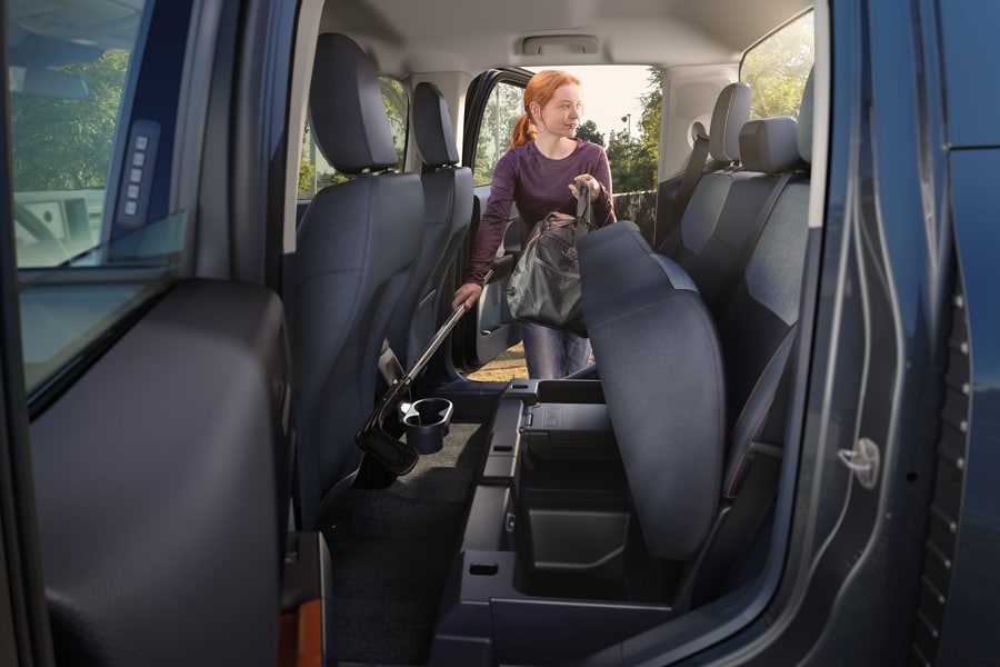 Mujer colocando un bolso en los compartimentos de almacenamiento debajo del asiento trasero de una camioneta Ford Maverick® 2023