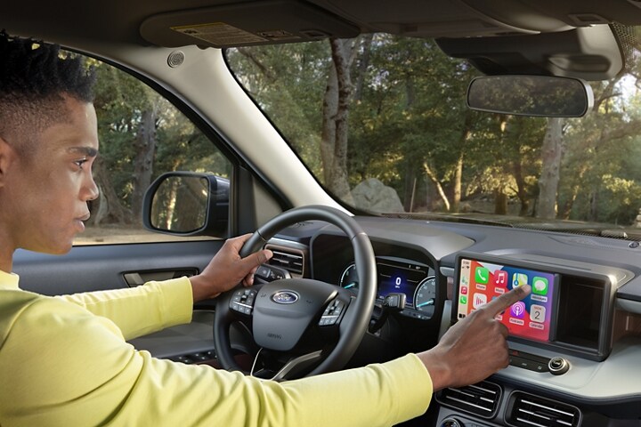 Man operating Apple CarPlay® touchscreen technology in a parked 2023 Ford Maverick® truck