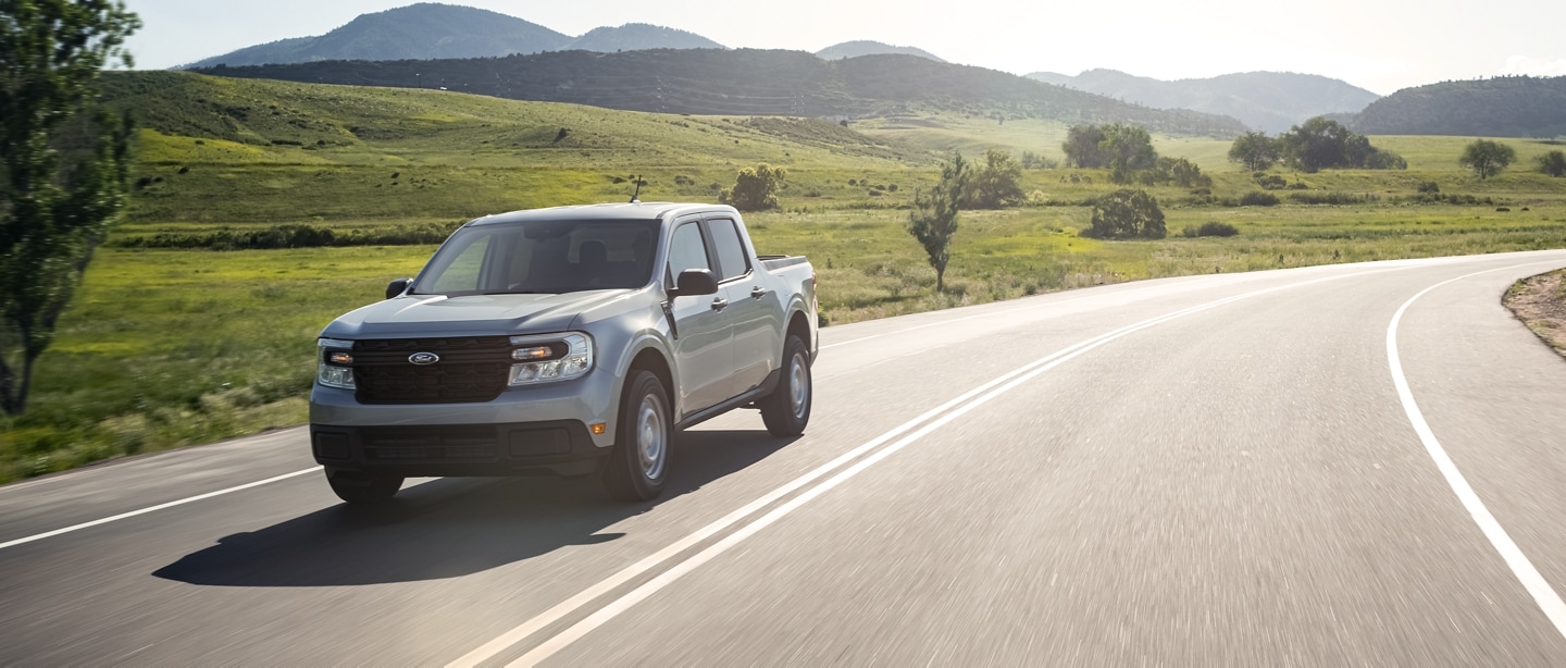 A 2023 Ford Maverick® truck on a country highway with hills in the background
