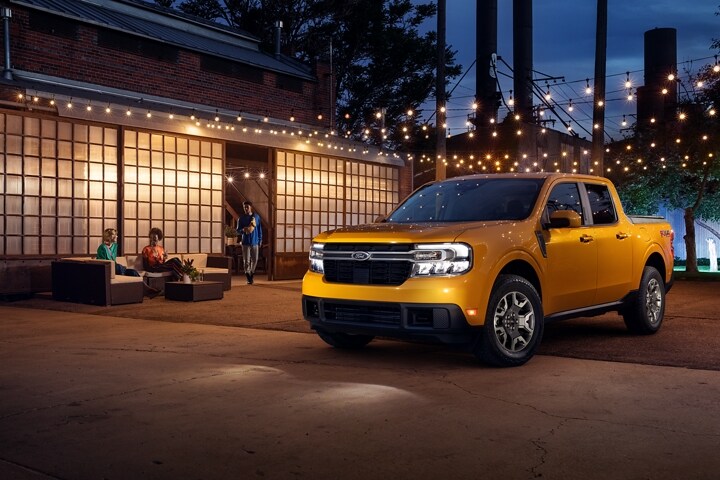 2023 Ford Maverick® truck parked outside a brick building with patio furniture and people out front