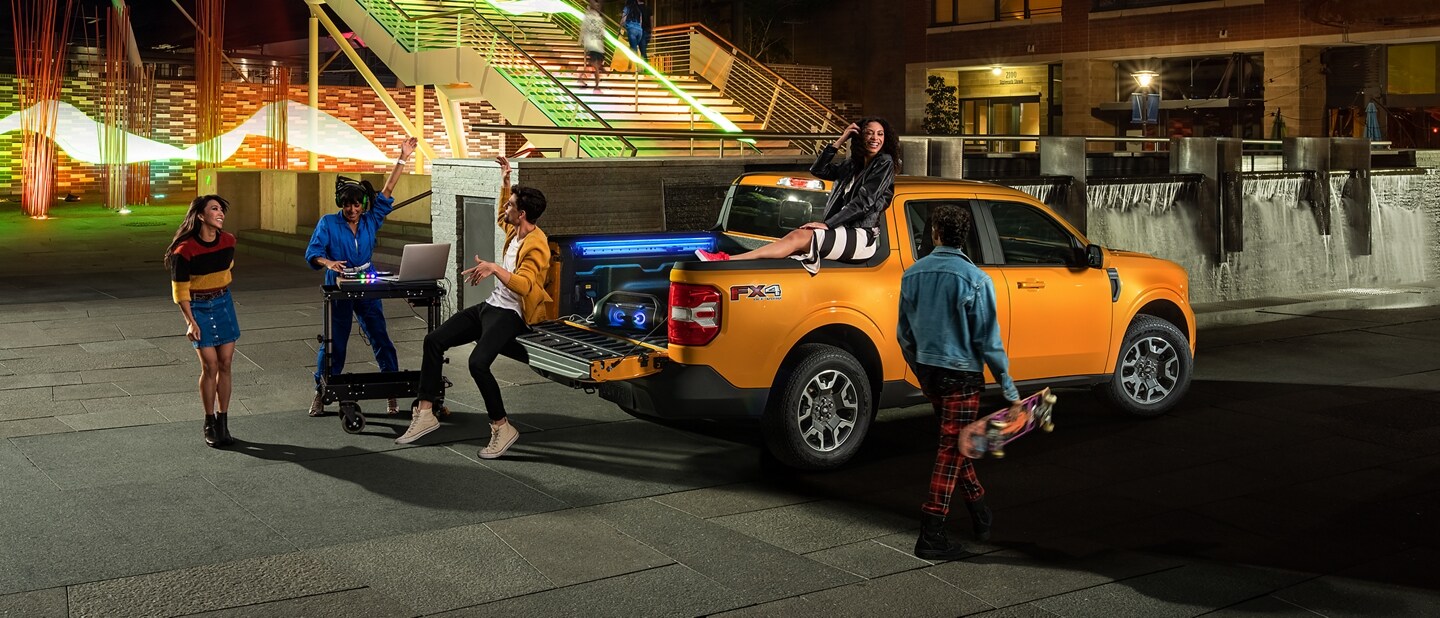 3 personas y un DJ en una fiesta al aire libre con su camioneta Ford Maverick® 2023 en Cyber Orange