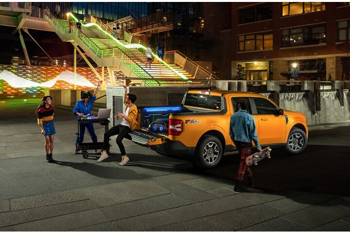 Two people and a DJ having a party with their Cyber Orange 2023 Ford Maverick® Truck
