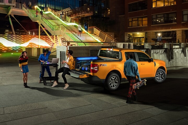 Dos personas y un DJ festejando con un Camioneta Ford Maverick® 2023 en Cyber Orange