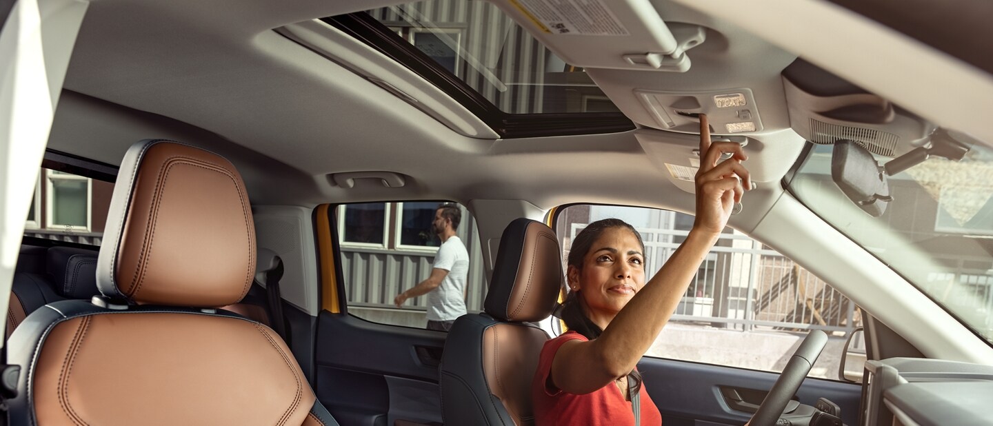 Woman operating the power moonroof inside the 2023 Ford Maverick® LARIAT model