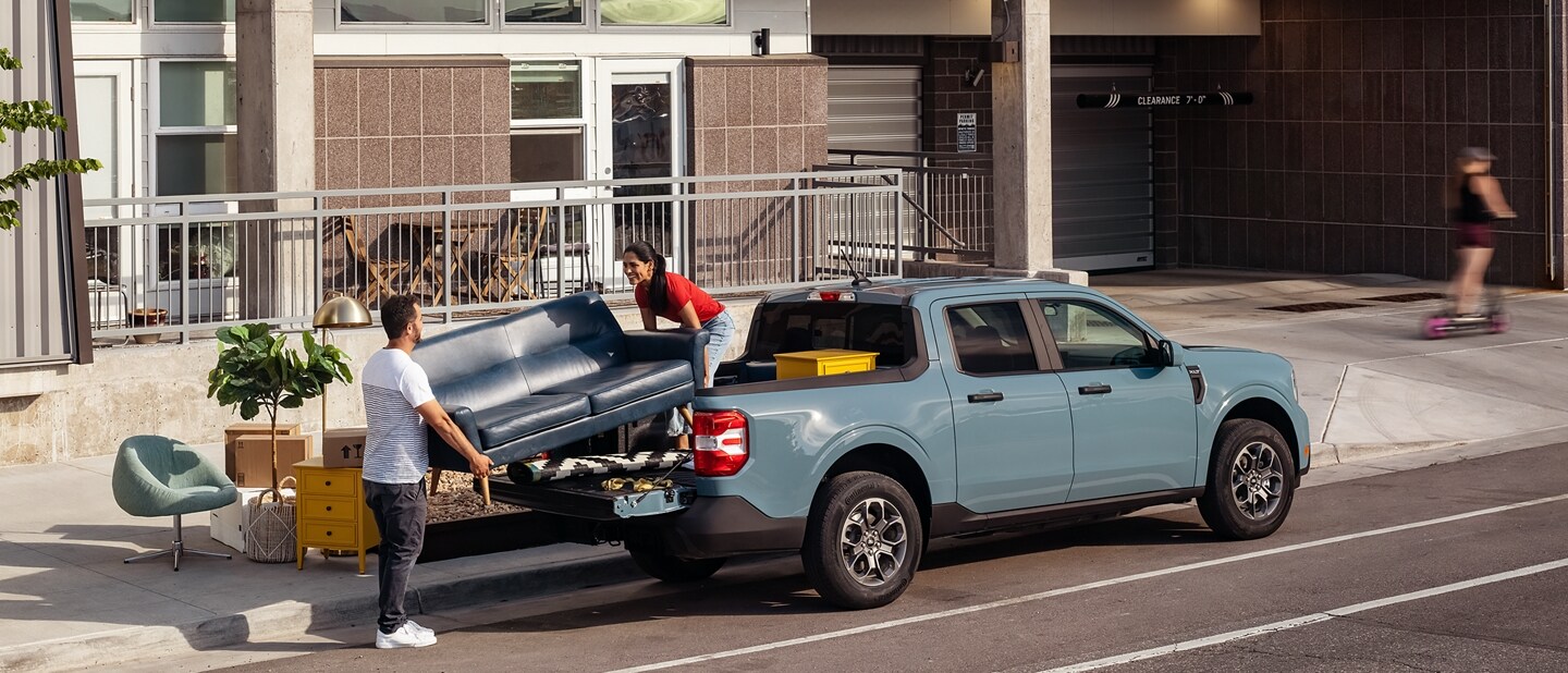 Two people unload a couch from the back of their 2023 Ford Maverick® truck in the color Area 51