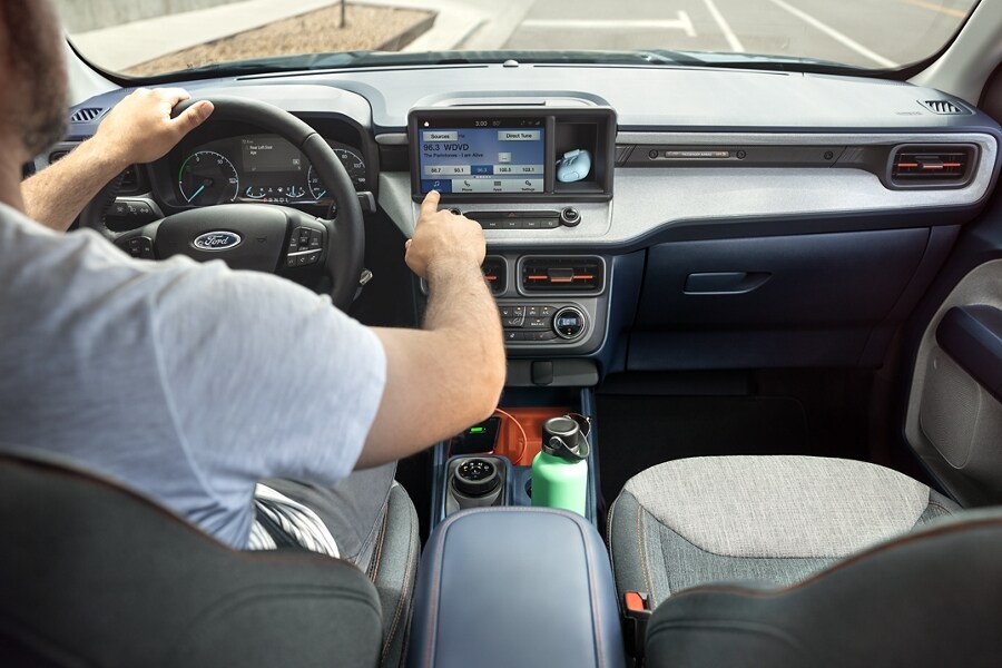 A 2023 Ford Maverick® XLT model with Navy Pier and Medium Slate interior with a driver using the eight-inch touchscreen