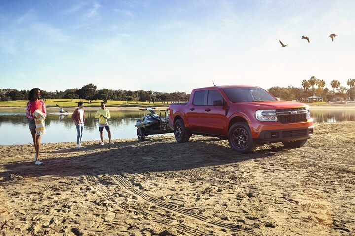 Hot Pepper Red 2023 Ford Maverick® truck on a beach loading a personal watercraft into the lake