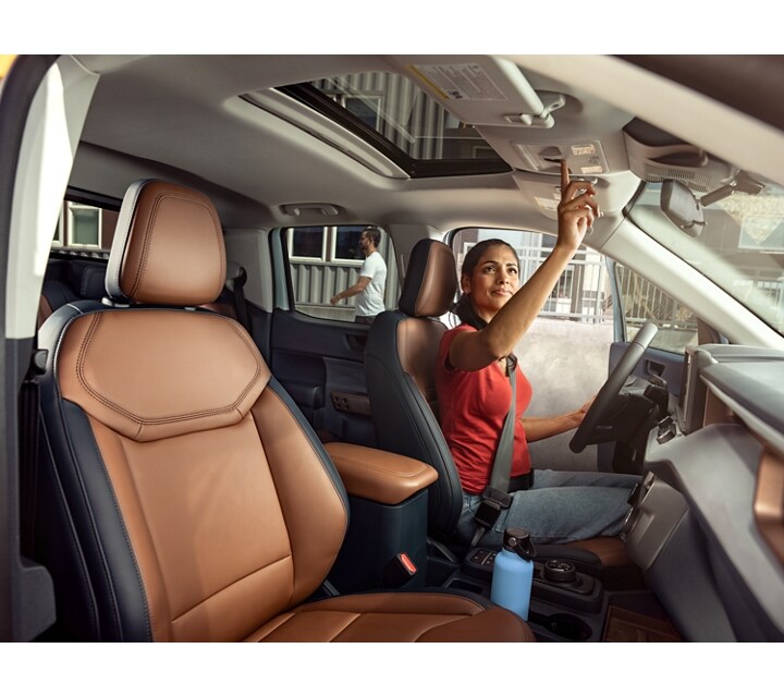 A person is engaged with the moonroof inside a parked 2024 Ford Maverick® LARIAT® model