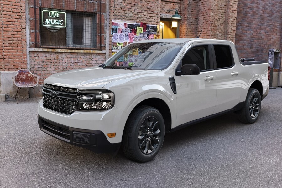 A 2024 Ford Maverick® LARIAT® truck with the Black Appearance Package is parked in front of a concert venue