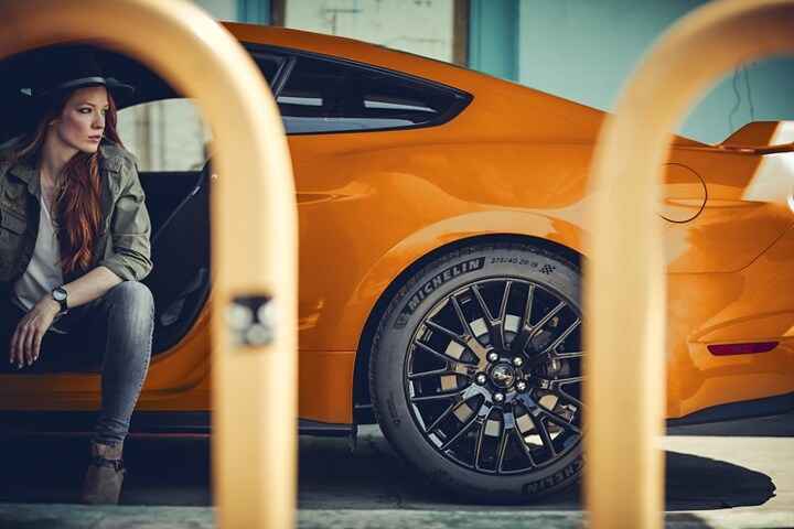 Woman sitting in a 2021 Ford Mustang G T in Twister Orange Metallic tinted clearcoat