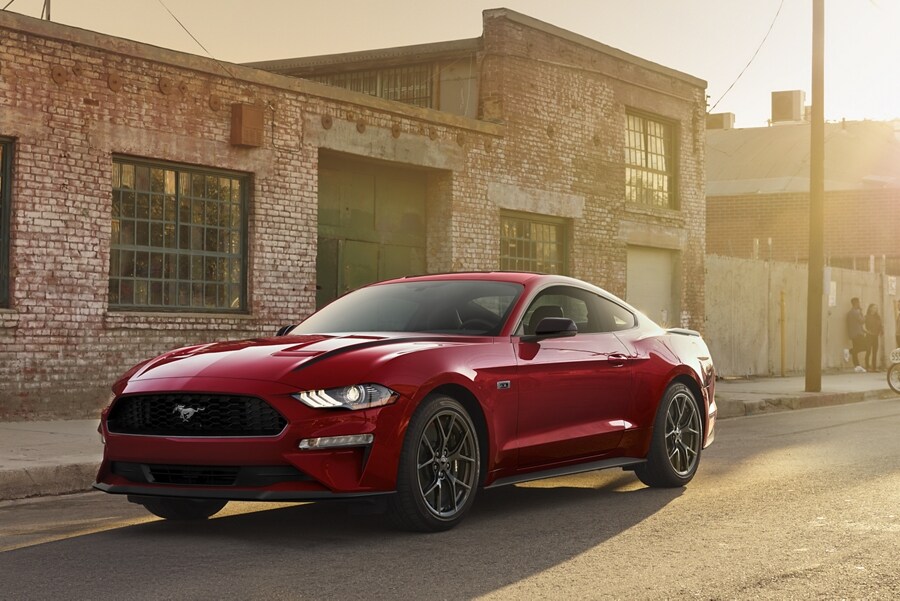 Un Ford Mustang® 2023 cupé estacionado en la calle frente a un edificio con frente de ladrillos