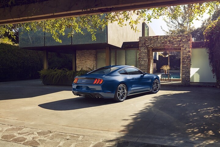 Una Ford Mustang® Coupe 2023 estacionada frente a una casa contemporánea elegante