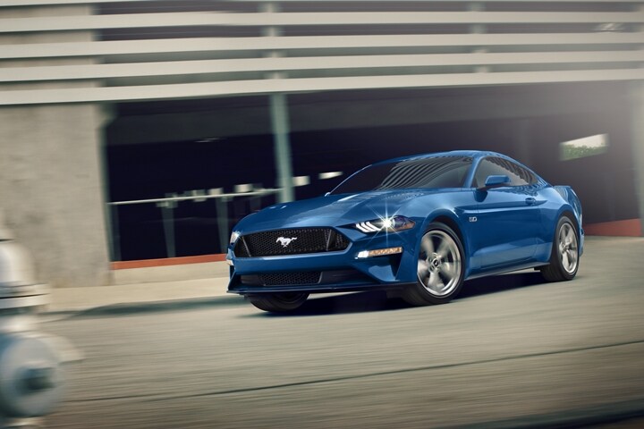 A 2023 Ford Mustang® GT Premium model in Atlas Blue Metallic being driven out of a parking garage