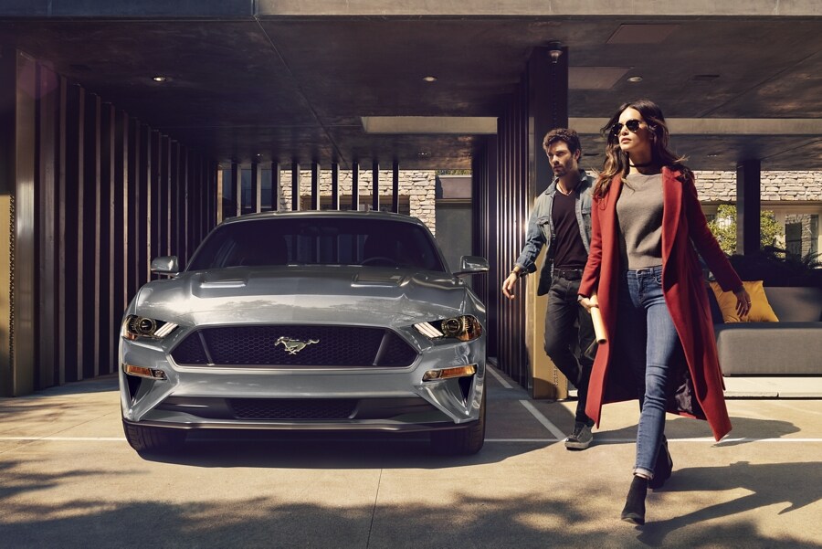 Un Ford Mustang® 2.3L 2023 con Paquete de Alto Desempeño en Iconic Silver Metallic estacionado en un garaje con dos personas caminando