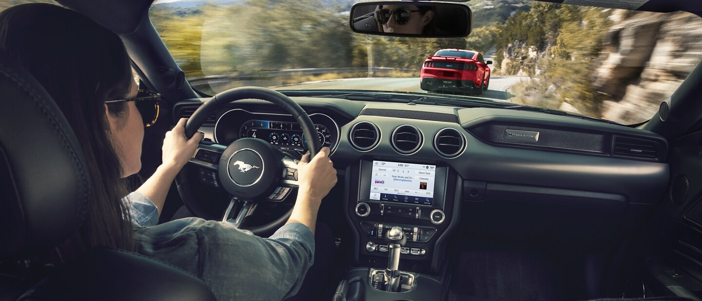 Una persona conduciendo un Ford Mustang® 2023 cupé por un camino de montaña