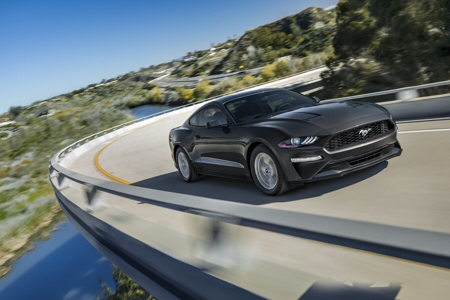 A 2023 Ford Mustang® coupe in Shadow Black being driven around a curve on a mountain road