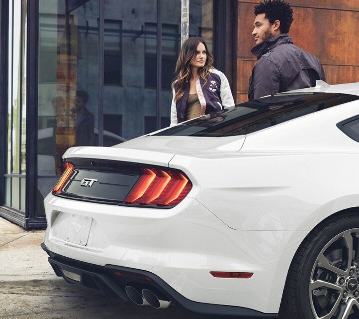 A 2023 Ford Mustang GT coupe parked on a street with four people nearby