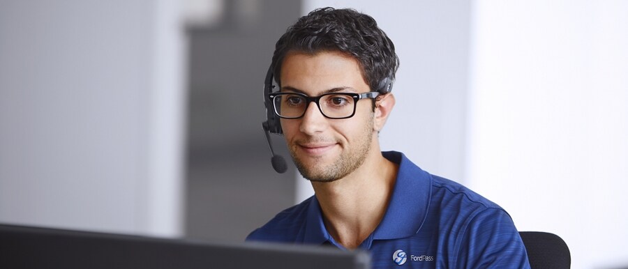 Person wearing microphone headset sitting in front of computer screen