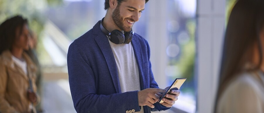 Person wearing headphones around their neck using a smartphone