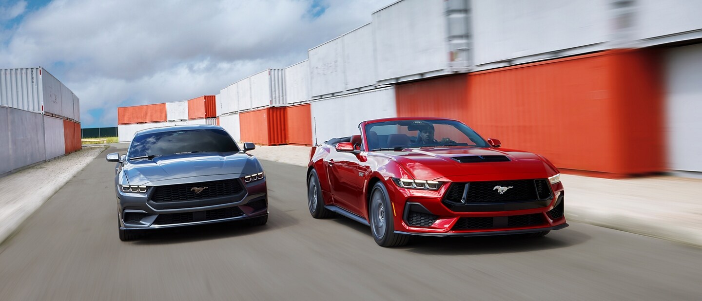 2024 Ford Mustang® coupe and convertible models being driven near shipping containers