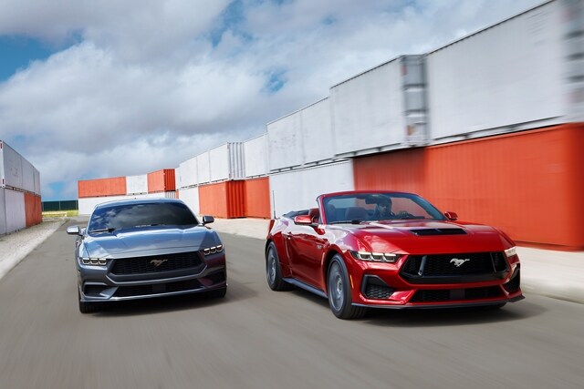 2024 Ford Mustang® coupe and convertible models being driven near shipping containers