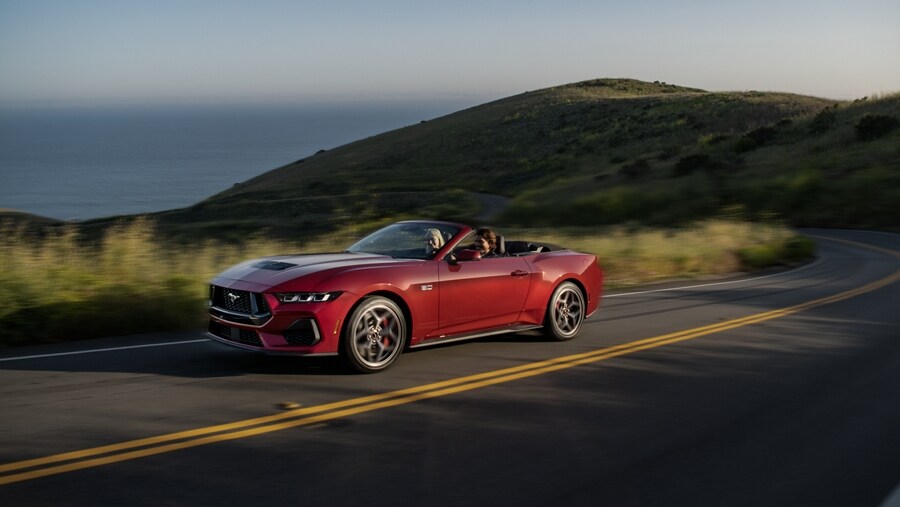 Two people driving a 2024 Ford Mustang® convertible on a highway