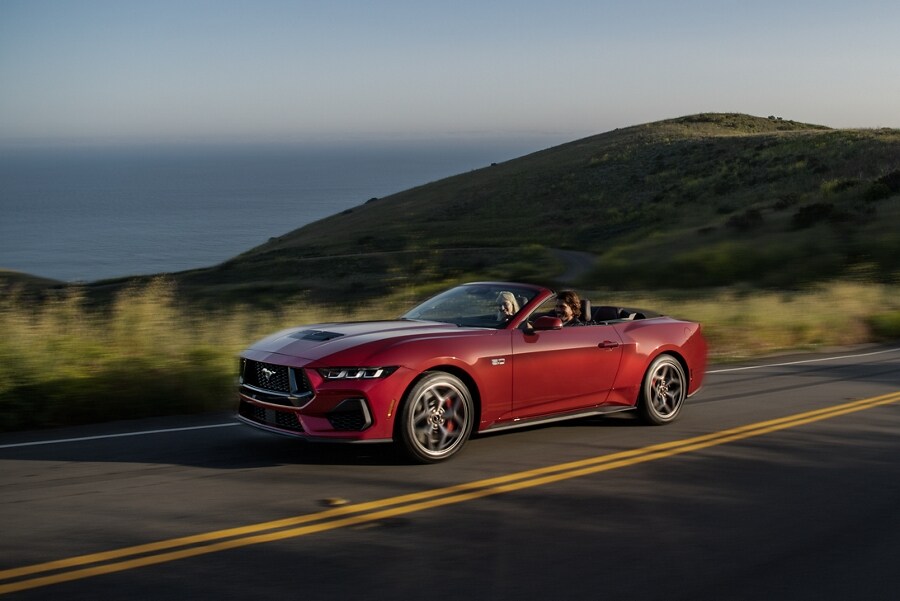 Two people driving in a 2024 Ford Mustang® convertible on a highway
